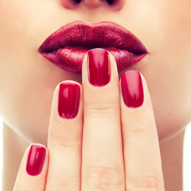Beautiful model shows red manicure on nails. Red lips .Luxury fashion style, manicure nail , cosmetics and makeup .