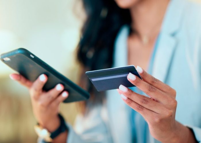 Bank card data put in phone by a lady who does internet banking by typing on her mobile to make an online credit payment. Young woman texting on her phone to send money via an ewallet transaction